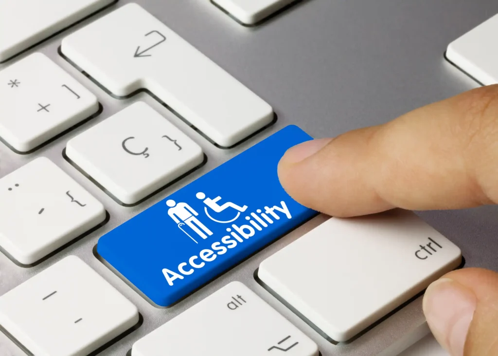Finger pressing a blue key on a computer keyboard labelled 'Accessibility'