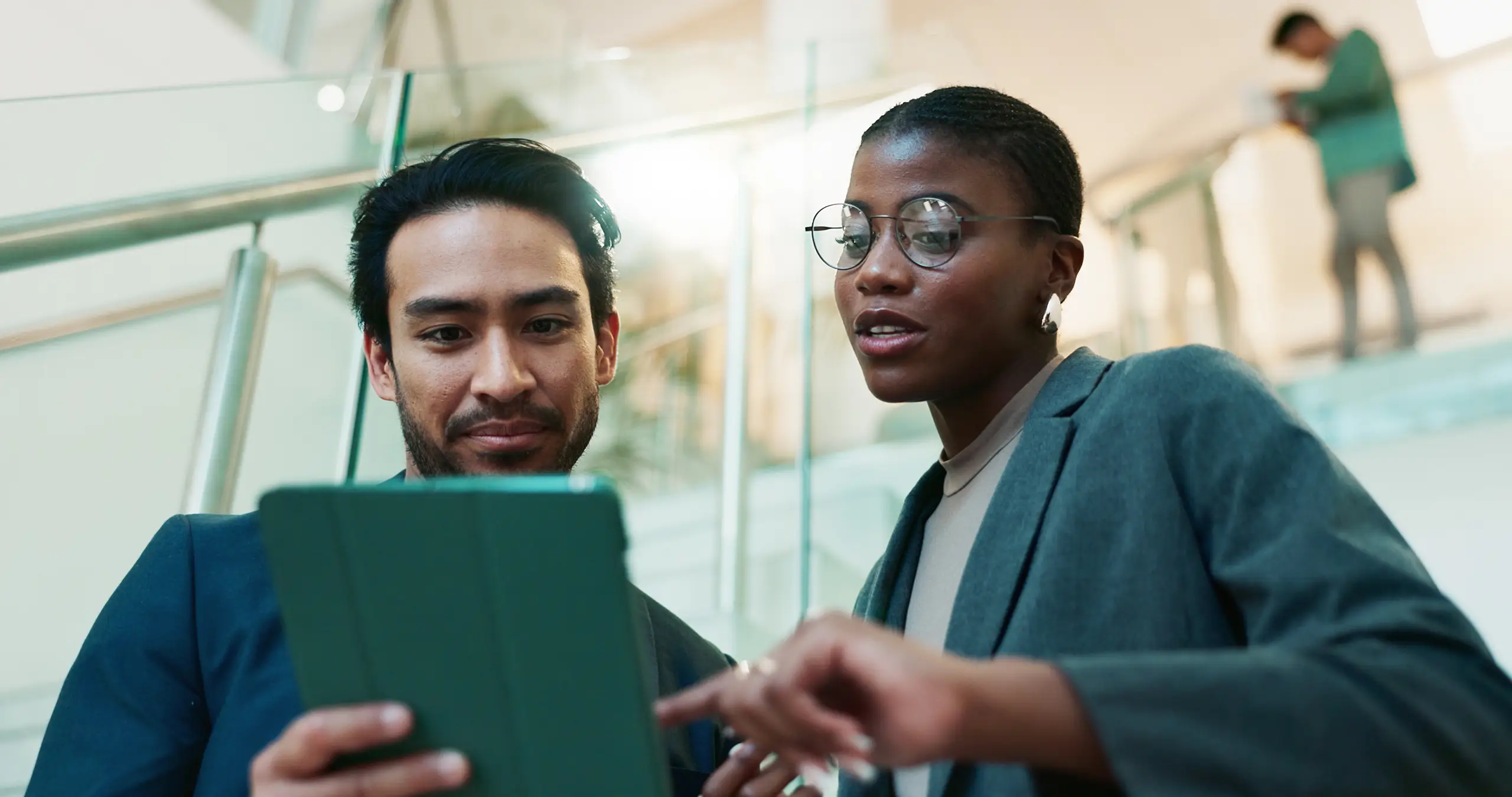 A man holding a tablet device with a women next to him pointing at the device