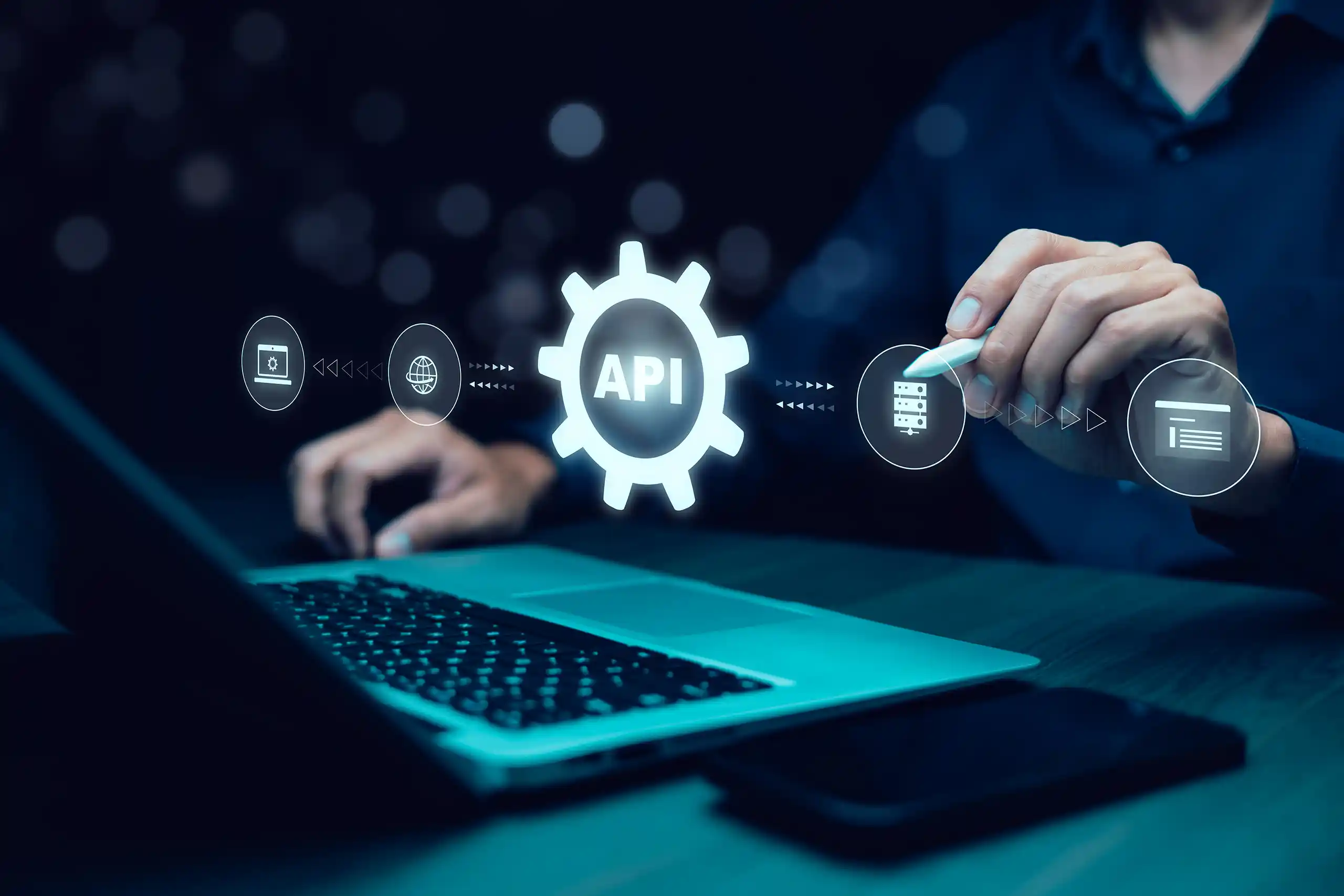 Person in front of a laptop using a stylus to point to a server icon on an overlaid graphic with other technology icons