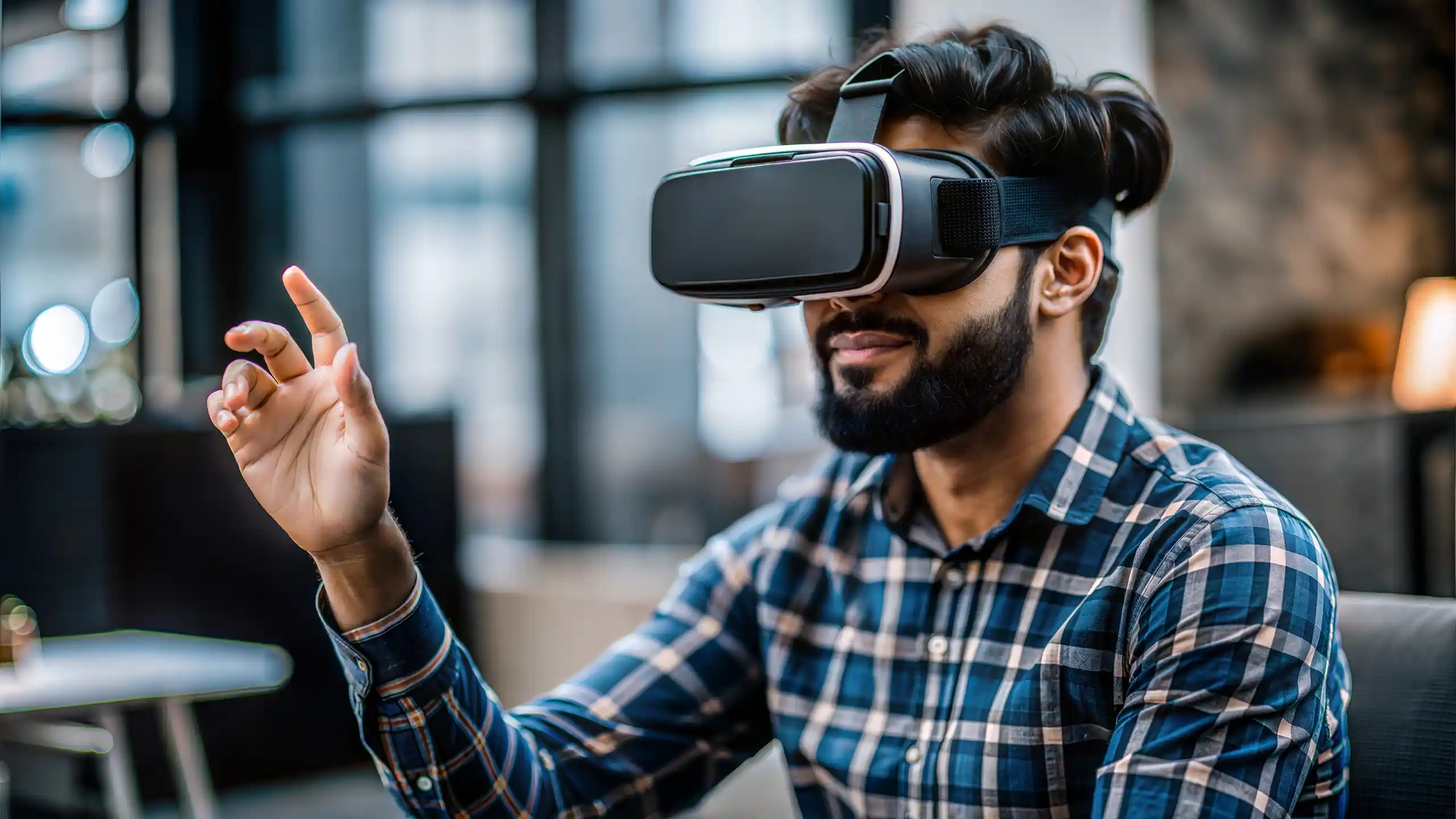 Bearded man with a checked shirt wearing virtual reality goggles with his right hand raised