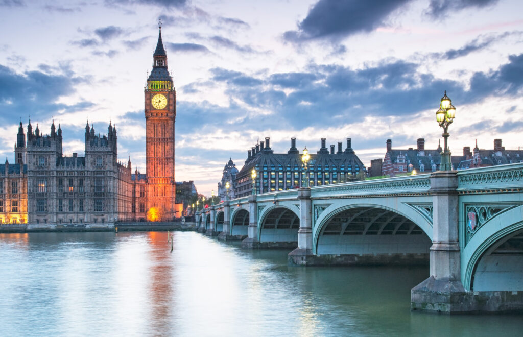 Big Ben and the Palace of Westminster next to the River Thames at dusk, with Westminster Bridge in the foreground — a clear, recognisable London landmark.