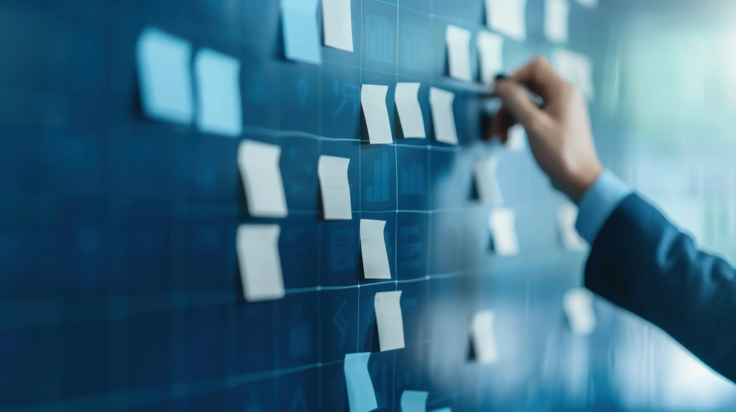 Person writing on a post-in note on a wall with other post-it notes